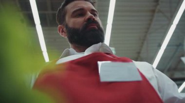 Süpermarkette sakallı, ciddi bir genç satıcının çerçevesini kapatın. Organik sebze pazarı, sebze, güzel emlak, tüketim ve tüketim ürünleri piyasası.