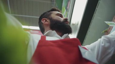 Süpermarkette sakallı, ciddi bir genç satıcının portre çerçevesi organik sebze pazarı, sebze, emlak, erkek tüketim ürünleri piyasası.