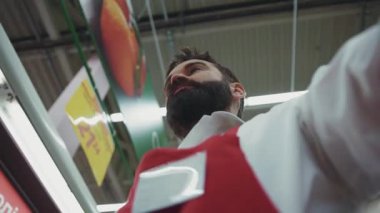 Süpermarkette çalışan ciddi sakallı genç bir satıcının çekici çerçevesi organik sebze marketi sebze pazarını piyasaya sürüyor.