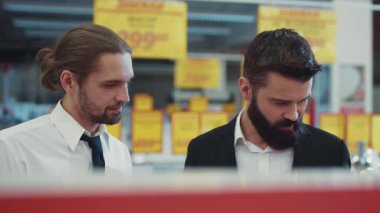 Teknoloji mağazasındaki genç sakallı adamla çekici satıcı sohbeti. Elektronik el alışverişi. İnternet alışveriş merkezi yavaş çekim portresi.