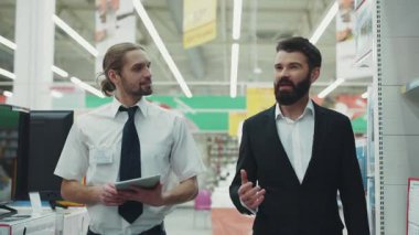 NEW YORK - 5 Nisan 2017: Genç sakallı adamla satış danışmanı konuşması. Teknoloji mağazasında el alışverişi elektroniği teknolojisi internet alışveriş merkezi yavaş çekim portresi.