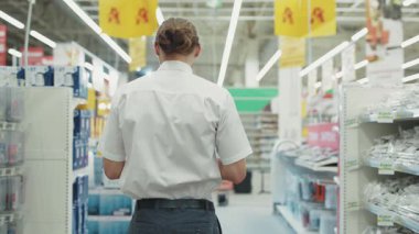 Çekici adam. Teknoloji departmanında satıcı dans ediyor. Süpermarkette tablet bilgisayar kullanıyor.