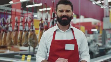 Süpermarkette sakallı bir portre satıcısı et reyonunda gülümse. Mutlu iş dünyası. Güzel, taze ürünler, perakende satış elemanı.