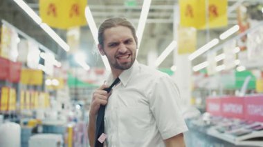 Yüzü yorgun, ciddi bir adam süpermarketteki teknoloji departmanındaki satıcı üzgün hissediyor kamera işi el alışverişi elektronik teknolojisi internetteki yavaş çekim yakışıklı portreyi kapat