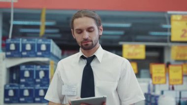 NEW YORK - 5 Nisan 2017: Satış elemanı, süpermarkette teknoloji bölümünde yürüyen tablet bilgisayar kullanıyor. Elektronik alışveriş merkezi, yavaş çekim.