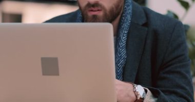 Dizüstü bilgisayar kullanan ve Noel ağacı yakınındaki alışveriş merkezinde oturan genç adam sıradan bir iş bilgisayarı, tasarım alışverişi internet yüz teknolojisi tableti yavaş çekim portresi