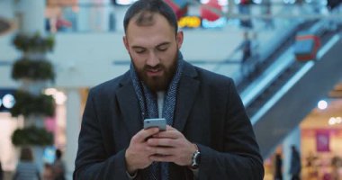 Yakın çekim genç adam gülümseyen telefon kullanın alışveriş merkezinde mutlu portre yakışıklı bekleyin alışveriş etrafında yılbaşı cep telefonu akıllı telefon gündelik internet