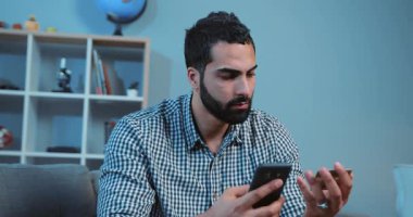 Çevrimiçi satın alan genç ve yakışıklı bir adam kanepe üzerinde bir telefon ve bir kredi kartı kullanıyor ev telefonu müşterisi kapanış aleti, yaşam tarzı akıllı iş dünyası internet teknolojisi bankacılığı nakit tutuyor.