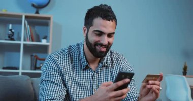 Çevrimiçi alan yakışıklı genç adam kanepe üzerinde bir telefon ve bir kredi kartı kullanıyor ev telefonu müşterisi kapatma cihazı el ele tutuşuyor akıllı iş dünyası internet teknolojisi bankası nakit