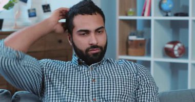 Yüzü yorgun, uykulu yakışıklı genç adam kanepede oturmuş TV 'ye bakıyor. Uyuyor, uyuyor. Canı sıkılıyor.