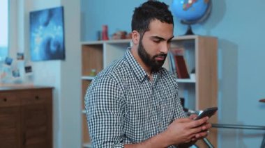 Ciddi ve çekici bir gencin portresi telefon kullan. Kanepeye otur. Akıllı telefon, elektronik uygulama.