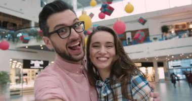 Mağazanın vitrinine erkek kıyafetleriyle bakan genç ve çekici bir adam. Yılbaşı için özel tasarım, Noel ağacı mağazası, alışveriş mağazası, yavaş çekim mağazası.