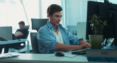 Ofisteki bilgisayarın başında oturan adam. Bilgisayar çalışmaz. Genç adam yardım masasını arıyor. Adam kızıyor..