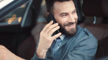 Güzel gülüşlü, arabalı ve camdan dışarı bakan hoş bir adam. Sakallı bir adam cep telefonuyla konuşuyor, gülüyor..