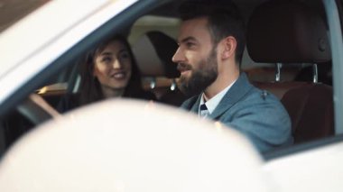 Yeni beyaz arabanın güzellik salonunda oturan sevimli iki genç insan. Çekici kız ve hoş adam konuşuyor, gülümsüyor..