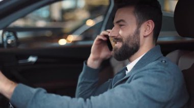 Siyah saçlı ve sakallı yakışıklı bir adam. Direksiyonda oturuyor ve cep telefonuyla konuşuyor. Gülen adam şaka yapıyor, yolu izliyor, pencereden dışarı bakıyor..