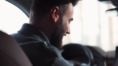 Direksiyonda oturan yakışıklı genç bir adam, bir şey söylüyor. Trafik sıkışıklığında kalan ve arabalara bakan bir adam. Yakın plan..