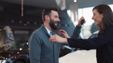 Genç adam güzel beyaz bir araba satın alıyor. Adam karısına yeni arabanın anahtarlarını gösteriyor. Güzel mutlu çift kucaklaşıyorlar, gülümsüyorlar..