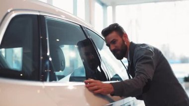 Günlük giysiler içinde araba almayı planlayan iyi bir adam. Genç adam mankeni dikkatlice görüyor, yan kapı ve camı inceliyor..