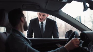 Arabada direksiyonda oturan genç adam. Genç danışman arabaya yaklaşıyor, bir şeyler söylüyor ve anahtarları veriyor. İlham veren adam gülümsüyor, alışveriş yapıyor..