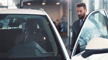 Sakallı genç bir adam yeni arabasında oturuyor. Güzel, gülümseyen kız arkadaş, erkeğin yanında oturuyor. Gençler konuşuyor, şaka yapıyor. Adam arabayı çalıştırıyor..