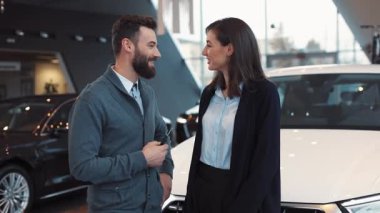 Sakallı genç adam yeni arabanın anahtarlarını elinde tutuyor. Adam şaka yapıyor ve kız gülüyor. Yeni arabanın arka planındaki kameraya bakan bir çift. Sarılmak..