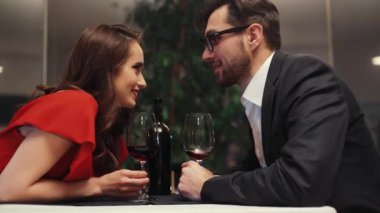 Harika bir kız ve yeşil bitkinin arka planında restoranda masada oturan sevimli bir adam. Randevu için güzel bir çift. Gülümsüyor.