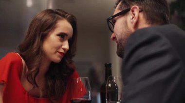 Kırmızılı zarif bayan sakallı yakışıklı adamın önünde oturuyor. Mutlu beyaz çift fısıldıyor, gülümsüyor, birbirlerine sevgi dolu gözlerle bakıyorlar..