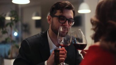 Masada güzel elbiseli çekici bir kızla oturan, kendine güvenen, gözlüklü yakışıklı genç bir adam. Siyah saçlı adam iltifat ediyor. Baştan çıkarma. Yakın plan..