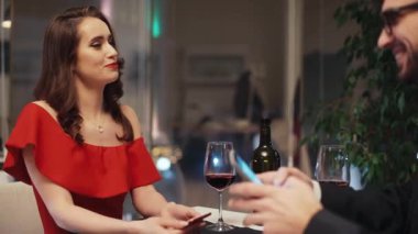 Restoranda masada oturan ve kendi akıllı telefonlarına bakan genç bir çift. Kız erkek arkadaşının mesajlarını göstermek istiyor. Şekerleme sahnesi. Modern tarih.