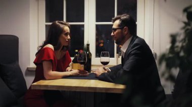 Aşk hakkında konuşan genç ve güzel bir çift. Kadın ve erkek kadeh tokuşturup şarap içiyorlar. - Şerefe. Buluşma yeri. Aşk hikayesi..