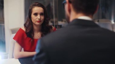 Pahalı takım elbiseli genç bekar Ukraynalı mankenle aynı masada oturuyor. Çift konuşuyor, gülümsüyor, şarap içiyor..