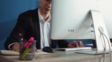 Gözlüklü yakışıklı genç Çinli ofis işindeki ekrana bakmak için bilgisayar yazıları kullanıyor. İnternetle yüz yüze gelen teknoloji işadamı. Laptop işadamı. Çekici iç, yavaş çekim yakışıklı.