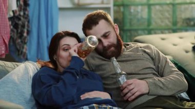 Birkaç alkolik erkek ve kadın kanepede oturup, içki içerler, içki içerler, erkek göbeği bağımlılığı yetişkin alkolikliği, tek başına depresyon, ağır çekimde stres portresi çekerler.