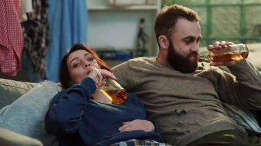 Alkolik genç adam ve kadın kanepede oturup uyurlarken içki içerken içki içerken içki içerken içki içerken yalnız karnında yetişkin alkolizmi tek başına stres portresi depresyonu ağır çekimde strese girer.