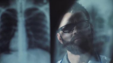 Sakallı, yakışıklı, beyaz bir doktor prestijli kliniğin muayenehanesinde röntgen çekiyor. Deneyimli bir doktor teşhis koyuyor. İçeride. Yakın plan..