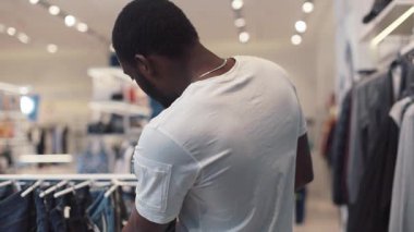 NEW YORK - 5 Nisan 2017: Yüzü Afro-Amerikan erkeği elbise seçti mağaza tasarımı mağaza tasarımı moda alışverişi güzelliği siyah günlük moda tarzı yakın plan kot pantolon yakışıklı