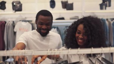 NEW YORK - 5 Nisan 2017: Çekici mutlu Afro-Amerikan çifti kıyafet mağazasından kıyafet seçiyor gülümseyen aile kadını moda alışverişi yapan adam kameranın genç sevgilisine bakıyor