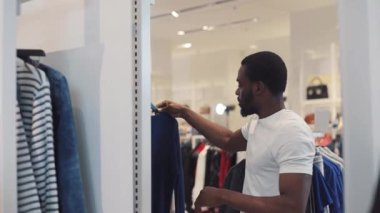 Çekici Afro-Amerikan erkeği, mağaza tasarımında aynaya bakarak kazağını seçiyor. Moda alışverişi güzellik, siyah giysi, gündelik model tarzı yakın çekim.