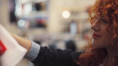NEW YORK - 5 Nisan 2017: Kapat yüzünü kıvırcık saçlı genç kadın mağazadan kıyafet seç gülümseme tasarımcısı çekici kız güzel, güzel kıvırcık saçlı portre yavaş çekim