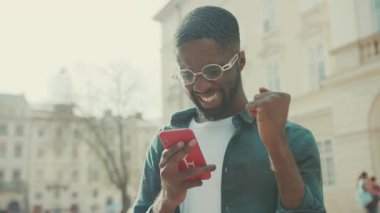 Yakışıklı Afro-Amerikan gözlüklü adam şehirde mutlu bir gülümseme teknolojisi kullanıyor iş adamları meşgul insanlar modern Blac yaşam tarzı hırslı cep telefonları