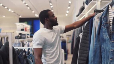 NEW YORK - 5 Nisan 2017: Afro-Amerikan erkek elbise seçiyor mağaza tasarımı, alışveriş merkezi tasarımı, moda alışverişi, güzellik, siyah gündelik moda tarzı kot pantolon yakışıklı ağır çekim