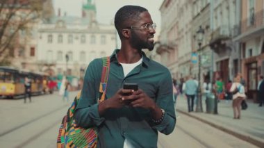 Gözlüklü Afro-Amerikalı telefonla geziyor şehir teknolojisinde iş adamları meşgul insanlar modern siyah kararlı yakışıklı yaşam tarzı akıllı telefon hırslı mobil bağımsız hareket