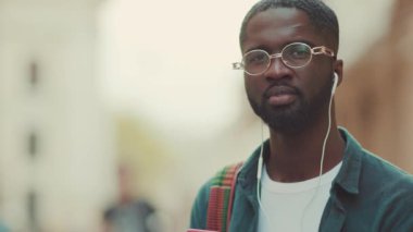 Moda yüz teknolojisi, siyah şehir kulaklıkları. Mutluluk caddesi. Çekici, yavaş çekim.