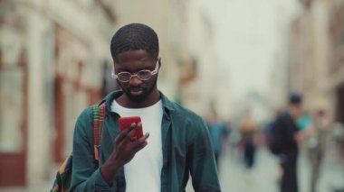 Portre Afro-Amerikan genç adam mutlu turist Avrupa 'da telefon kullanıyor yakışıklı sokak şehirli zenci gülüşü Bireysellik cep telefonu günbatımına yakın