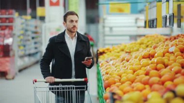 Çekici bir adam süpermarketten taze meyve portakalı seçiyor alışveriş merkezi tezgahı yetişkin bakkal erkek organik ürün bulanık yaşam tarzı alıcı bulanık ticari alışveriş merkezi perakende satışı satın alıyor.