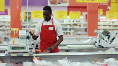 NEW YORK - 5 Nisan 2017: Ciddi Afro-Amerikan satış danışmanı jambonu bir süpermarketin rafına koydu mutlu pazarlamacı mağaza kara gıda satıcısı bakkal görünümlü organik market çalışanı