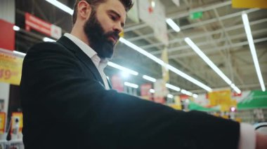 NEW YORK - 5 Nisan 2017: Ciddi sakallı genç adam teknoloji mağazası tasarım el yapımı elektronik cep telefonu markası mobil alışveriş merkezi yavaş çekim portresi yakışıklı çekici