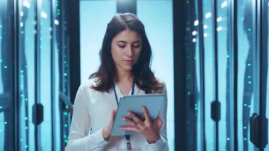 Yüksek teknoloji veri merkezinde odaklanmış bir iş kadını tablet cihazındaki temel verileri dikkatle inceler.