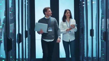 Sayısız sunucuyla dolu yüksek teknolojili bir veri merkezinde, iki yetenekli profesyonel çözümleri tartışmakla meşgul.